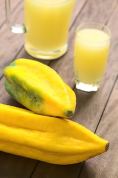 Two Ecuadorian Babaco fruits (lat. Vasconcellea x heilbornii; syn. Carica pentagona) with babaco juice in the back. Babaco is a fruit which is mainly used to prepare juices in Ecuador. (Selective Focus, Focus on the tip of the upper and the front of the lower fruit)