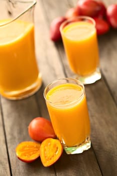 Fresh juice out of tamarillo fruits (lat. Solanum betaceum) on a table outdoors (Selective Focus, Focus one third onto the surface of the juice)