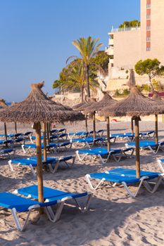 Beautiful Sandy Beach with Straw Umbrellas at Sunrise in Paguera, Majorca ( Balearic Islands - Spain )