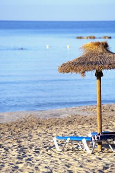 Beautiful Sandy Beach with Straw Umbrellas at Sunrise in Paguera, Majorca ( Balearic Islands - Spain )