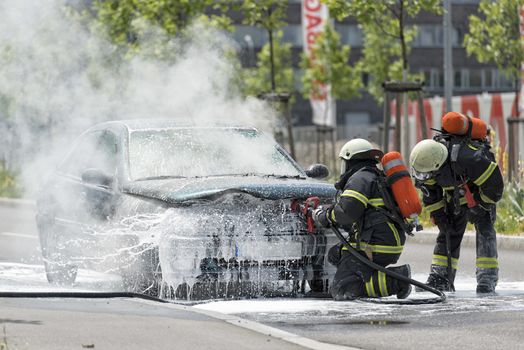 FREIBURG, GERMANY - JUNE 09: Firefighters are just putting out a burning and smoking car on the street on June 09, 2013 in Freiburg, Germany. No one was injured.