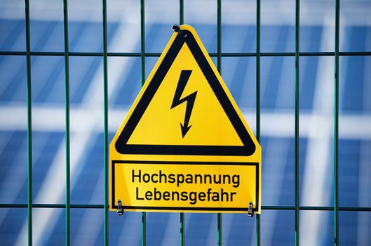 Danger Electrical Hazard High Voltage Sign With Solar Panels in the Background