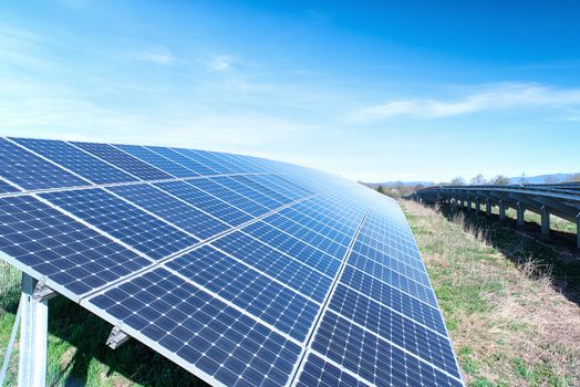 Field with many solar cells in front of a blue sky