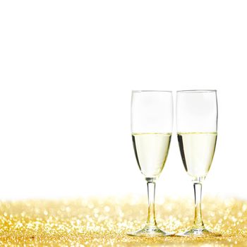 Pair of champagne flutes on shiny glitter background