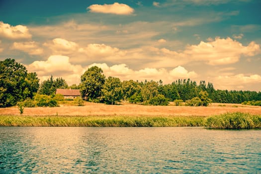 House by a riverside surrounded by fields and trees