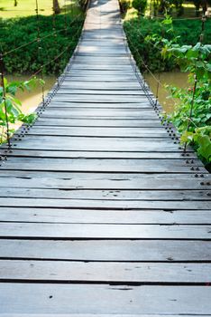 Wooden long rope bridge cross the stream in green tropical nature
