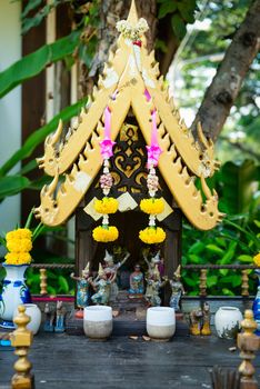 Small spirit house in Thailand with flowers and statuettes