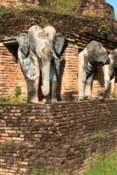 Elephants statues on ruins of Buddhist stupa or chedi in Sukhothai historical park in Wat Chang Lom temple. 