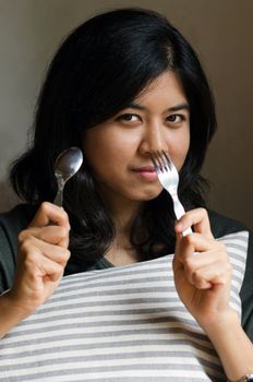 Asian woman with spoon and fork