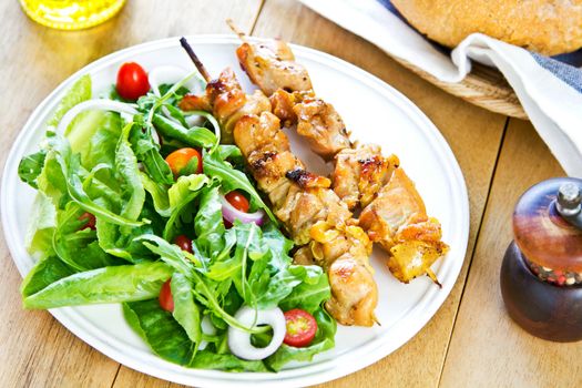 Grilled chicken skewer with rocket salad by bread