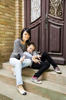Happy mother and daughter on the stairs at the house door