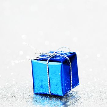 Blue holiday gift on silver glitter background