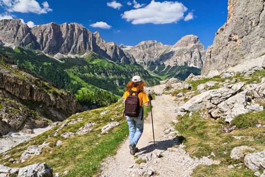 hiker on footpath  in Sella mountain, on background Colfosco and Badia Valley, south Tyrol, Italy