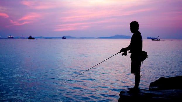 Silhouette of fishing man beside the sea