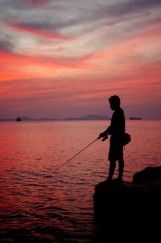 Silhouette of fishing man beside the sea