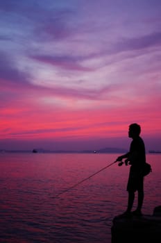 Silhouette of fishing man beside the sea