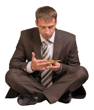 Businessman sitting in lotus position and hold gold lamp. Isolated on white background