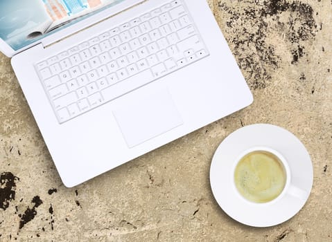 Laptop and coffee cup on old concrete surface. Computer technology concept