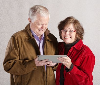 Happy older man and woman holding a tablet computer