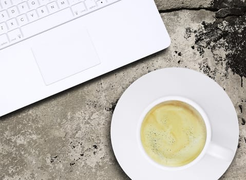 Laptop and coffee cup on old concrete surface. Computer technology concept