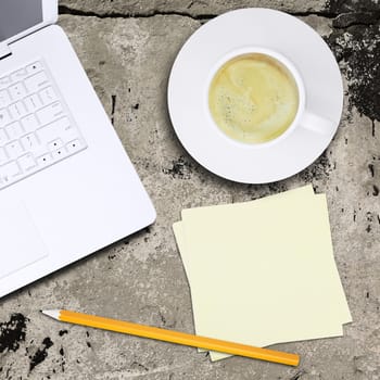 Laptop and coffee cup on old concrete surface. Computer technology concept