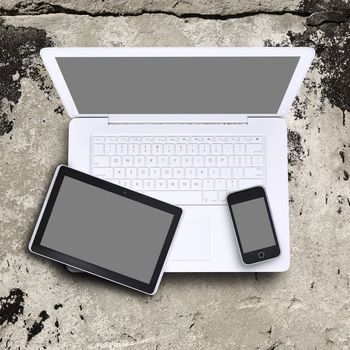 Laptop, tablet pc and smartphone on old concrete surface. Computer technology concept
