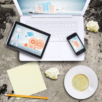 Laptop, smartphone, tablet pc and coffee cup on old concrete surface. Computer technology concept