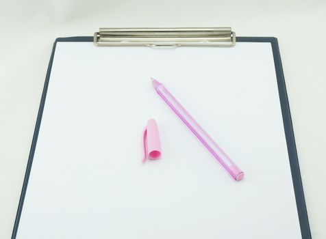 The white paper note plugged on the blue board, pink pen and pen cap placed on top.                              