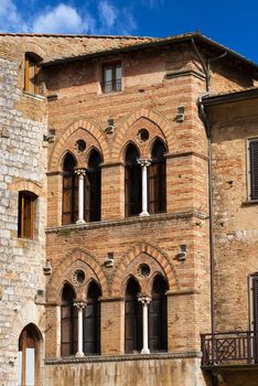 Old Buildings on the Cisterna square on blue sky, San Gimignano medieval town (UNESCO heritage), Siena, Tuscany, Italy