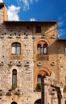 Old Buildings on the Cisterna square on blue sky, San Gimignano medieval town (UNESCO heritage), Siena, Tuscany, Italy