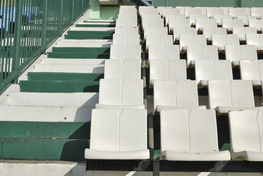 Rows of broken and stained white chairs in an outdoor auditorium