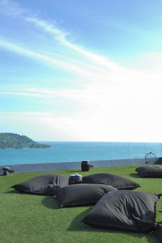 Comfort black cushion outdoor on green grass seaview in blue sky.