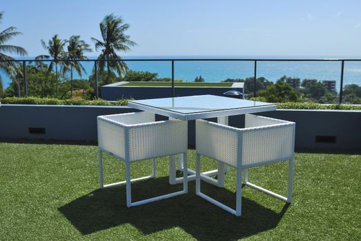 Terrace lounge with white rattan armchairs and seaview in a luxury resort .