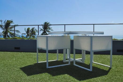 Terrace lounge with white rattan armchairs and seaview in a luxury resort .