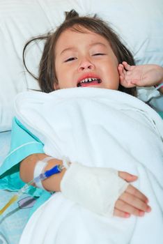 Sick little girl crying in hospital bed