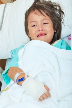 Sick little girl crying in hospital bed