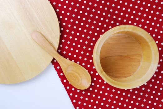 Wooden bowl, tablecloth, spoon, fork on table background