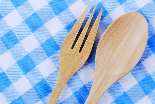 Wooden spoon,  tablecloth, fork on table background
