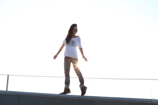 Young girl on the roof relaxes in the rays of the setting sun