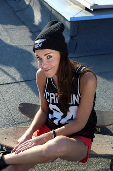 Young girl on the roof relaxes in the rays of the setting sun