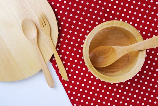 Wooden bowl, tablecloth, spoon, fork on table background