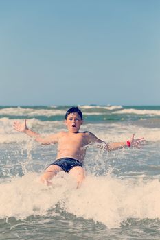 Happy boy running and jumping at shallow sea water, retro color tone
