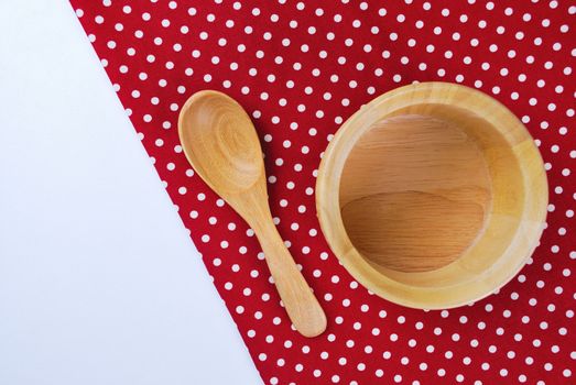 Wooden bowl, tablecloth, spoon, fork on table background