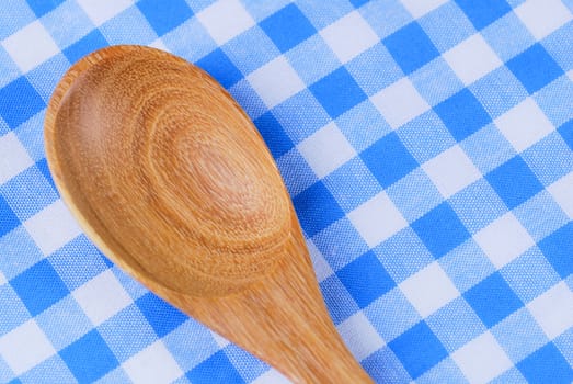 Wooden spoon,  tablecloth, fork on table background