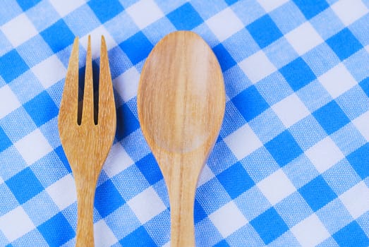 Wooden spoon,  tablecloth, fork on table background