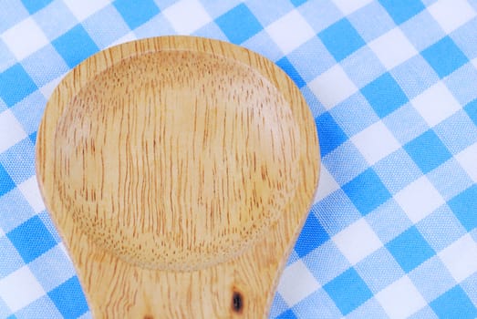 Wooden spoon,  tablecloth, fork on table background