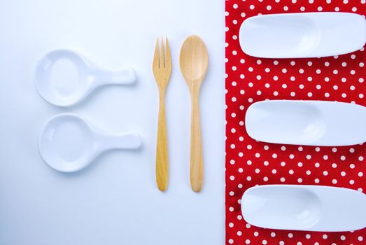 Wooden plate, tablecloth, spoon, fork on table background