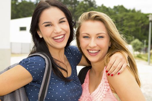 Two beautiful and happy teenage students lauthing 