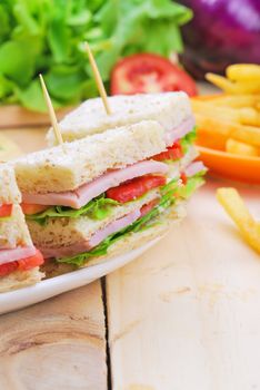 Club Sandwich with Cheese, Pickled Cucumber, Tomato and ham. Garnished with French Fries