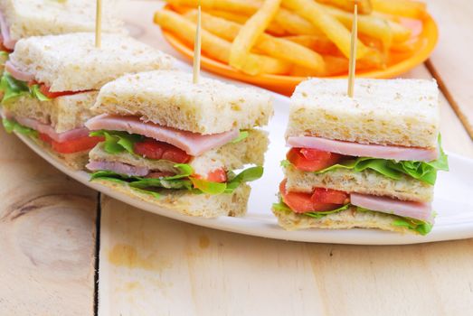 Club Sandwich with Cheese, Pickled Cucumber, Tomato and ham. Garnished with French Fries